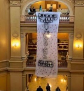 Kansas, Governor Laura Kelly, Medicaid, protst, banners, blood on their hands, Kansas Statehouse